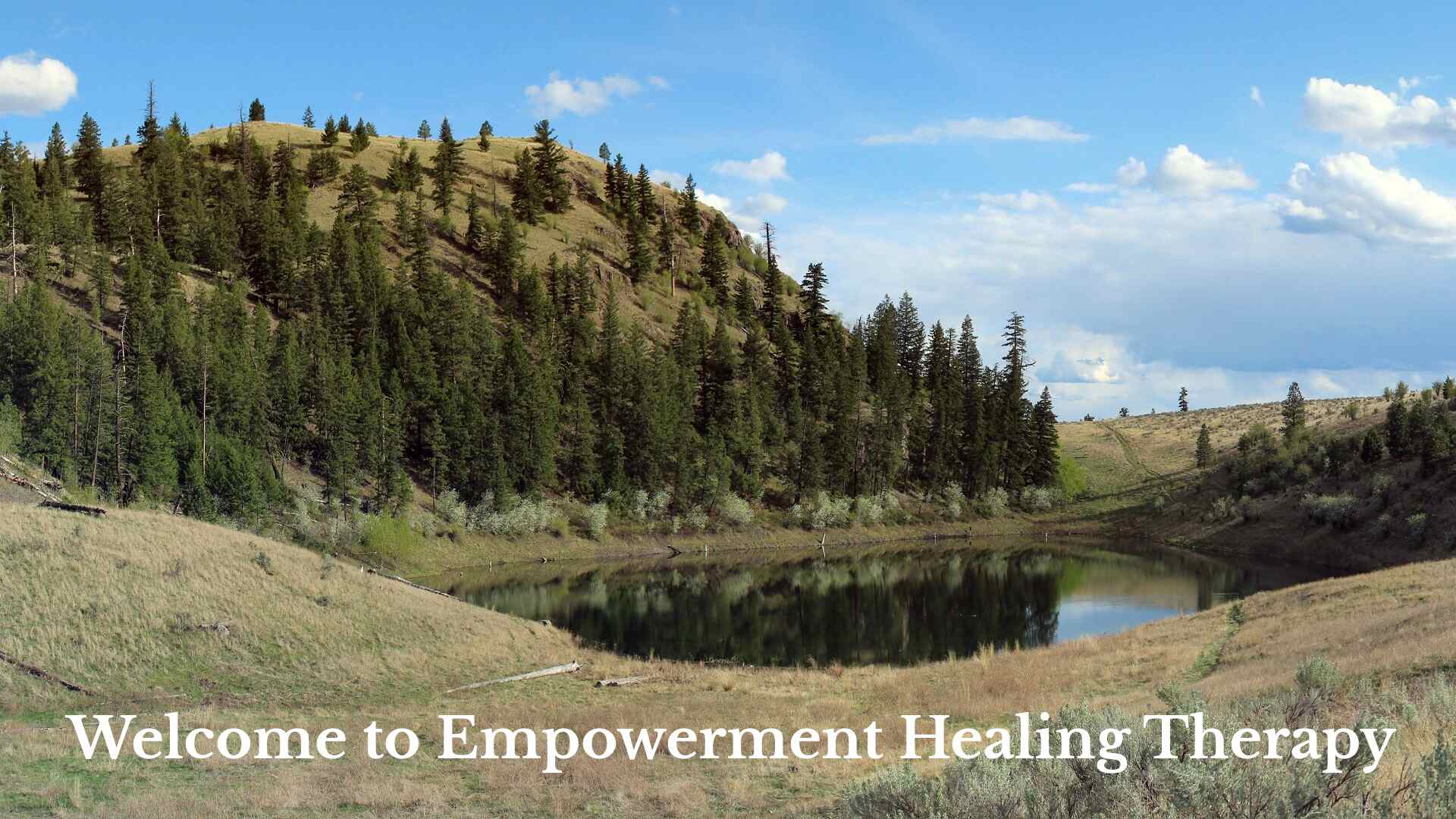 A landscape of blue skies and rolling hills with trees surround a small lake with the text Welcome to Empowerment Healing Therapy